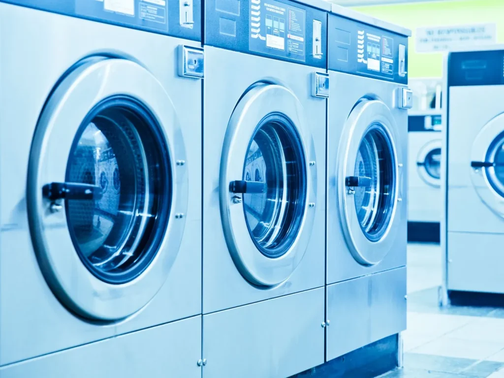 Row of front loading washing machines in a bright laundromat